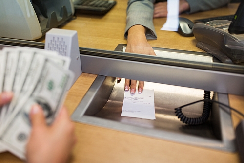 bank clerk giving receipt to customer with money